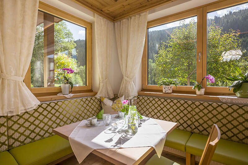 Sitzecke und schön gedeckter Tisch im Frühstücksraum in der Pension Zillertal